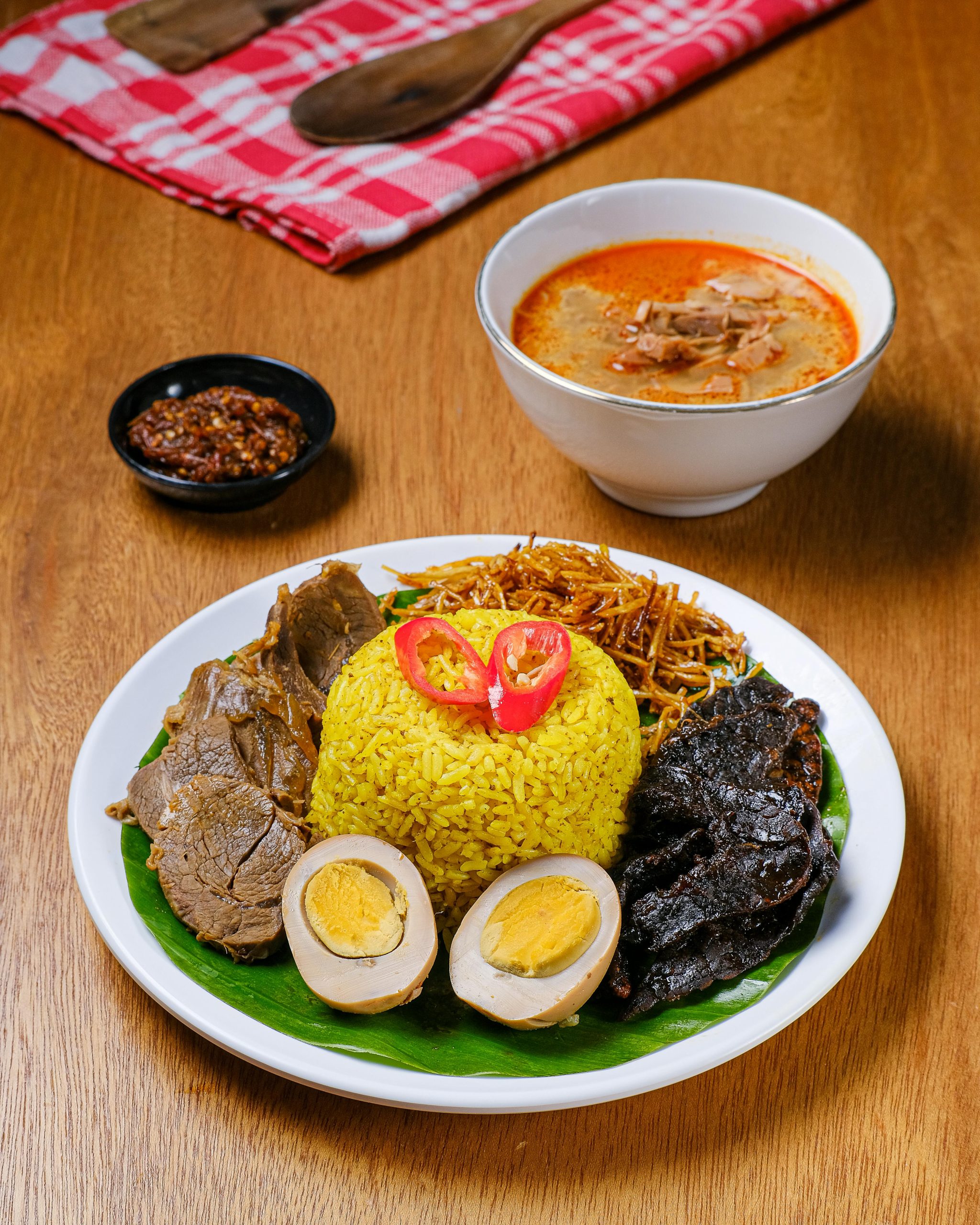 Delightful Nasi Kuning with Rendang, sambal, and coconut soup, a traditional Indonesian feast.