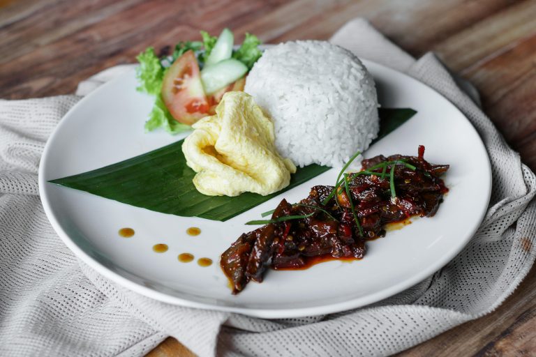 Delicious Indonesian platter with rice, omelette, and spicy beef rendang.